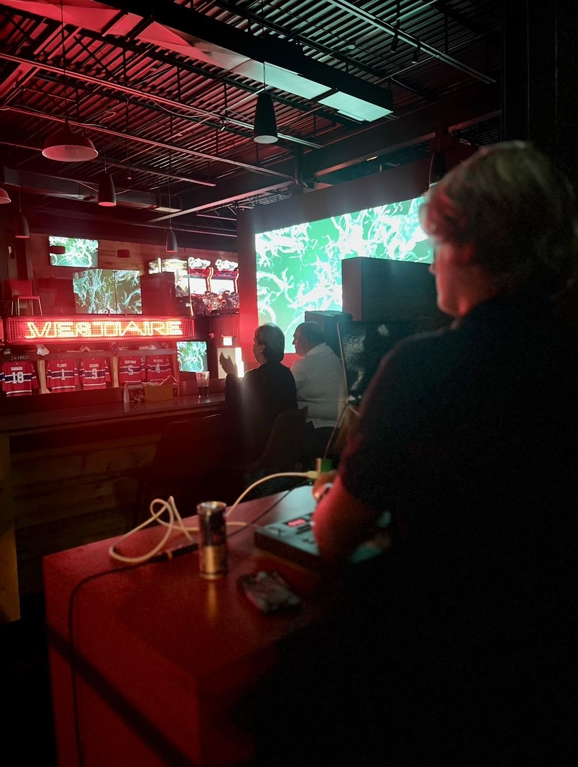 Technicien à la régie pendant une soirée dans un bar, écrans et éclairage rouge